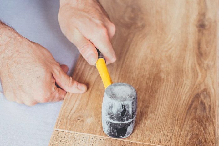 Mit einem Gummihammer wird Klick-Vinyl festgeklopft.